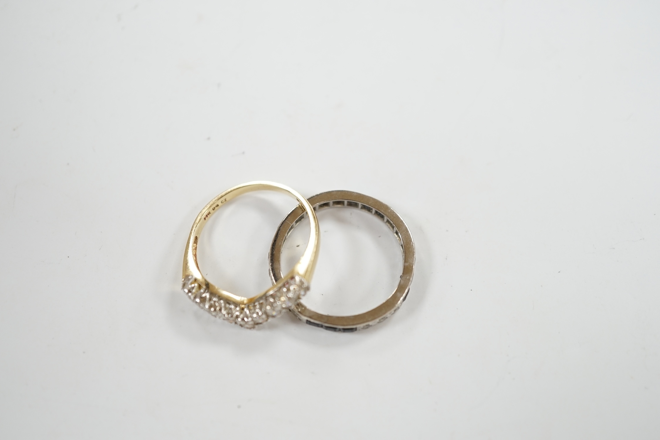 A white metal sapphire and diamond set full eternity ring, size Q/R, gross weight 3.6 grams, together with a 14k and cubic zirconia set chevron ring, gross 2.8 grams. Condition - fair to poor